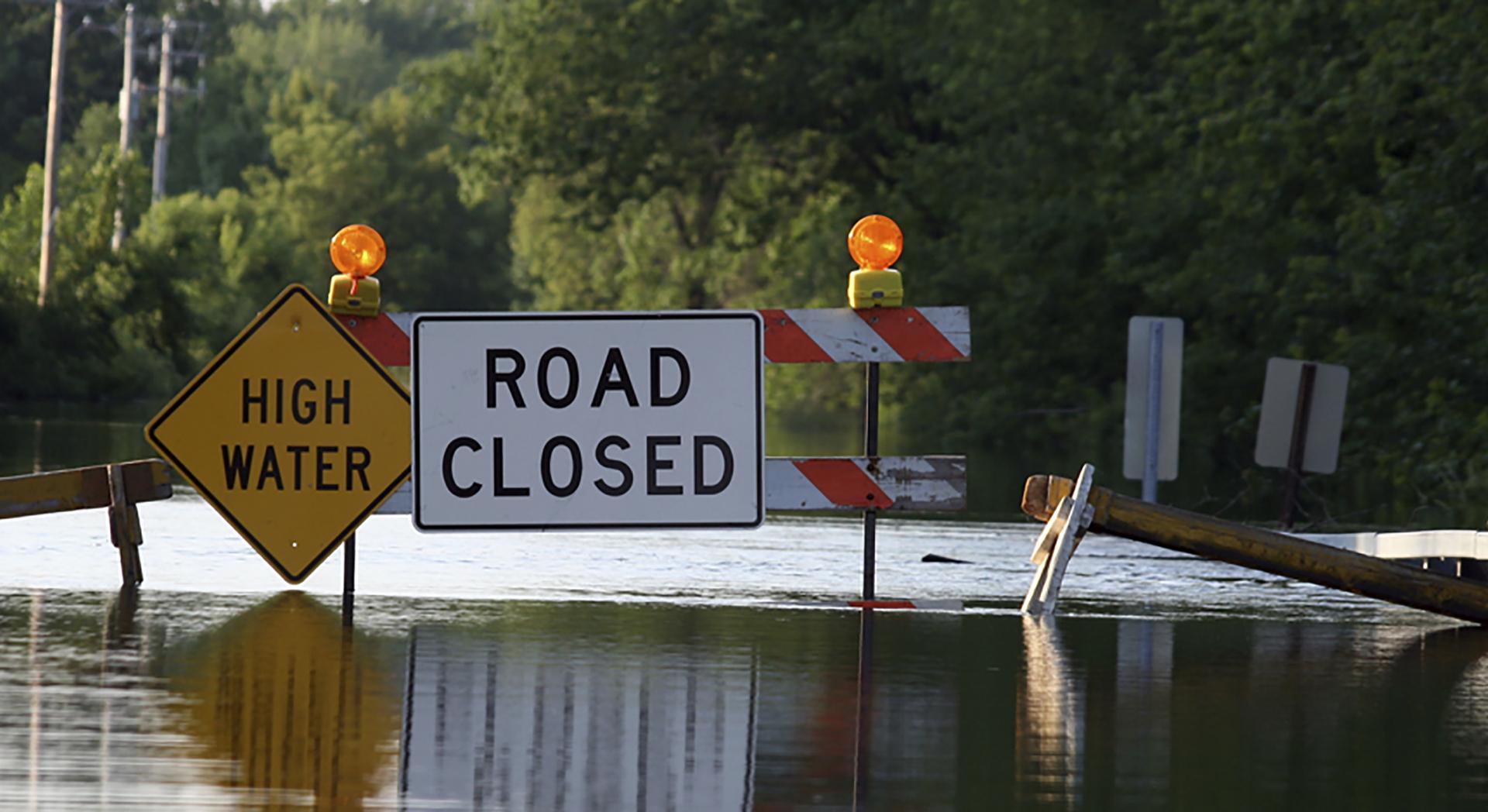 Image of flooded road with signage saying High Water and Road Closed