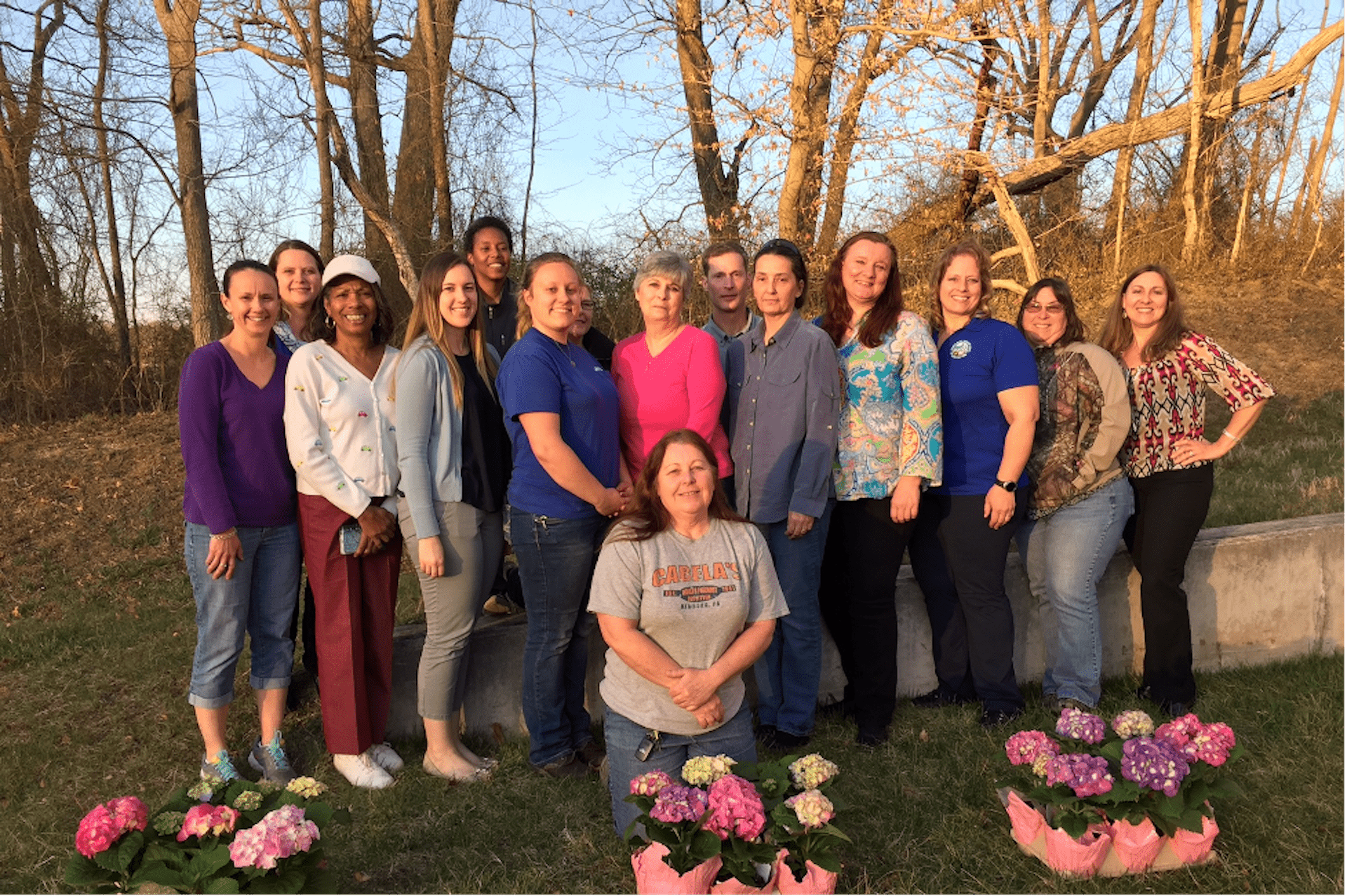 Annie's project class standing in front of trees with flowers in front of them