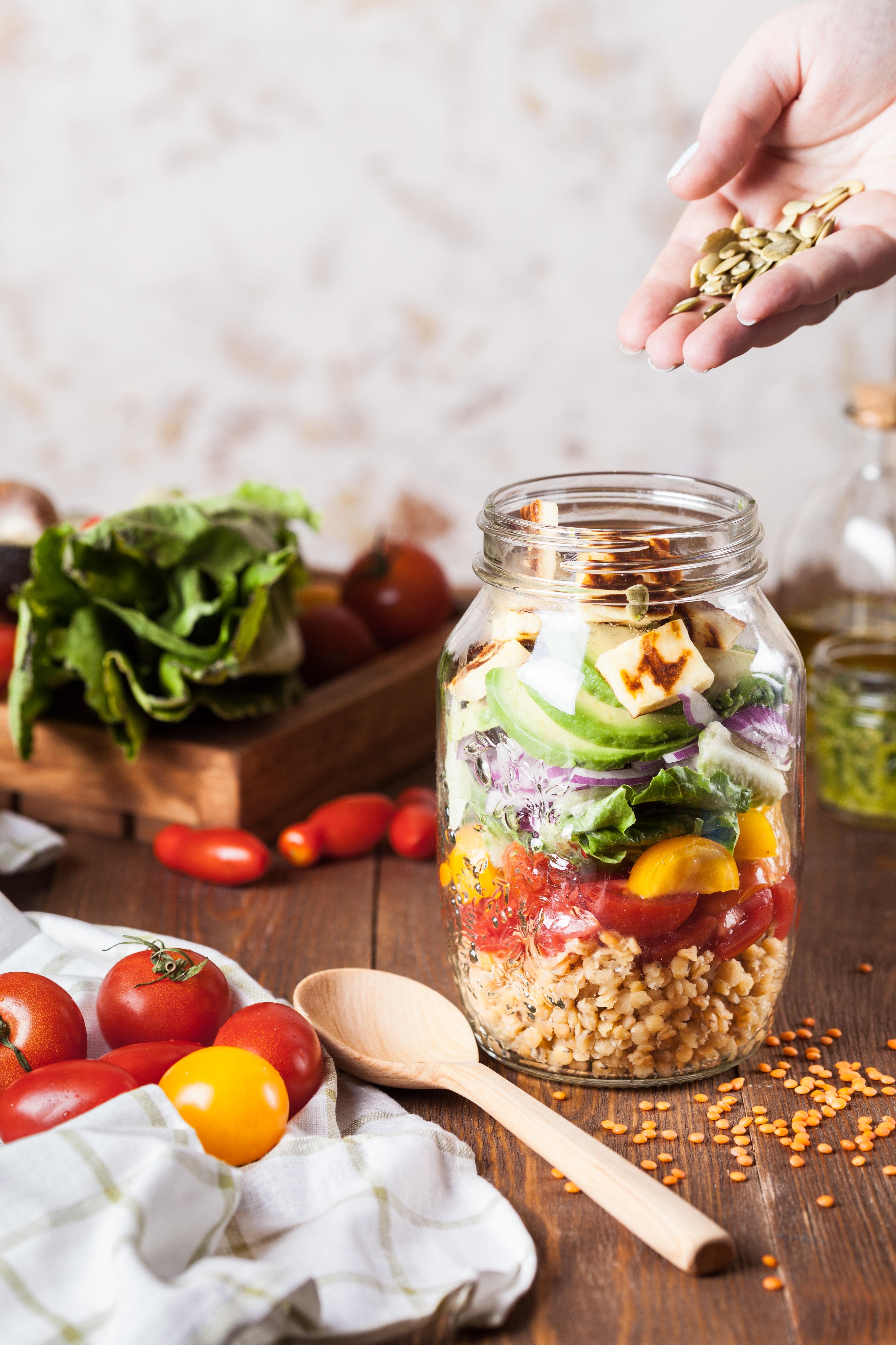 a colorful salad in a jar surrounded by vegetables