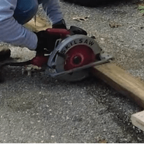 A person is using a circular saw to cut treated lumber