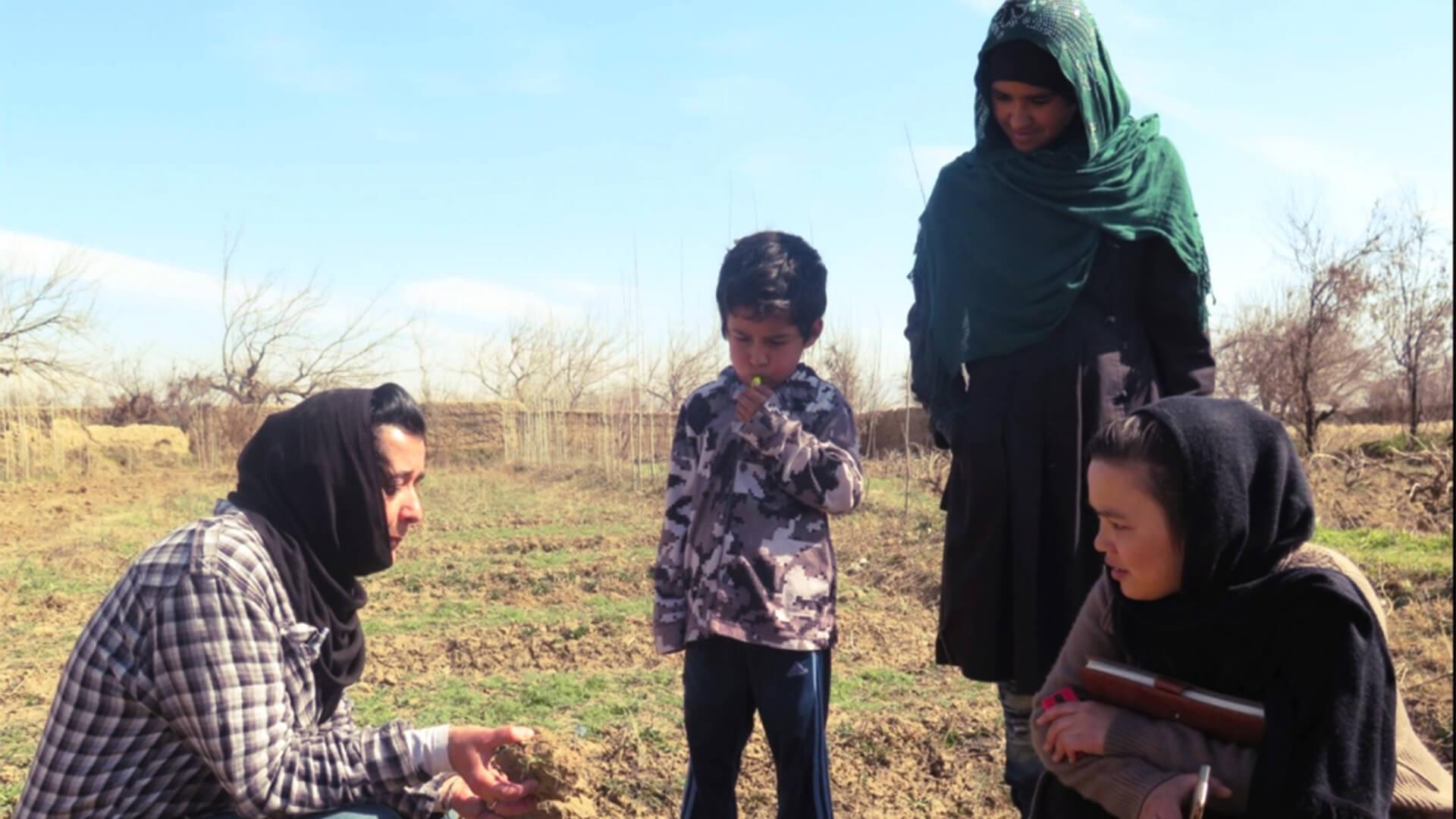 Women in a field looking at soil in their hands