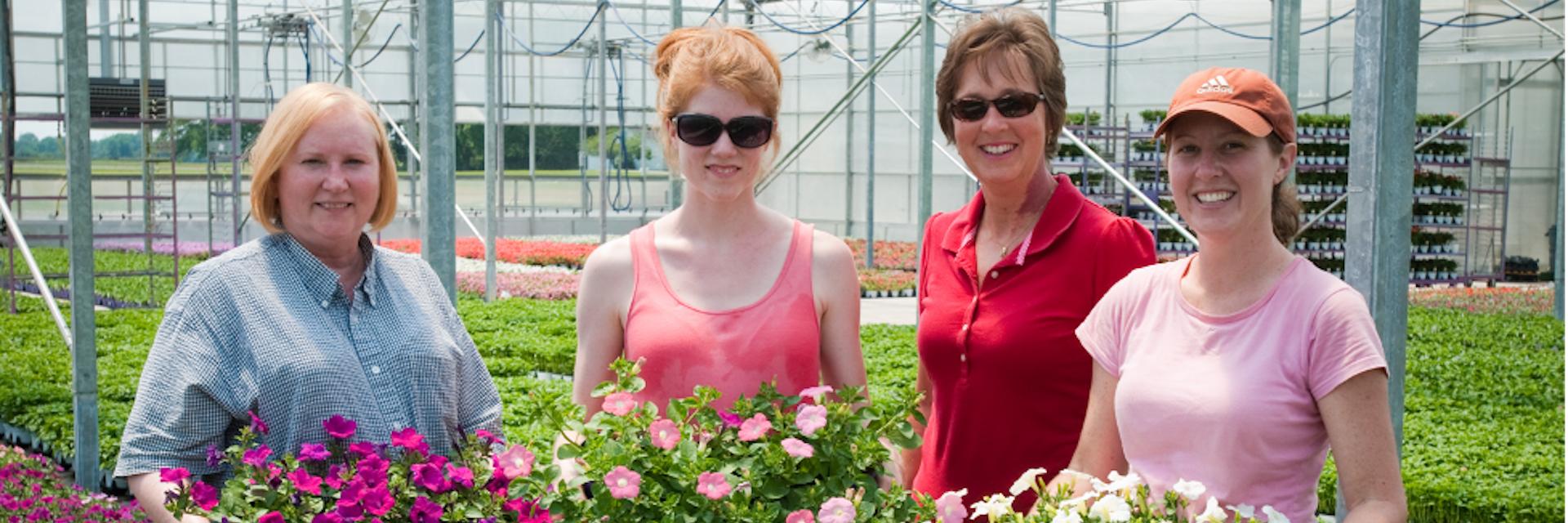 Group of women farmers holding flowers in greenhouse