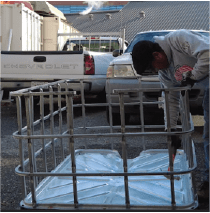 A person is bending over the IBC frame using a hammer to align the frame to the platform.